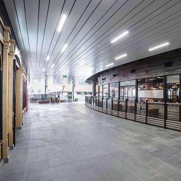 KNAUF Ceiling Armstrong F-Plank metal panel in store corridor with microperforated linear strip panels