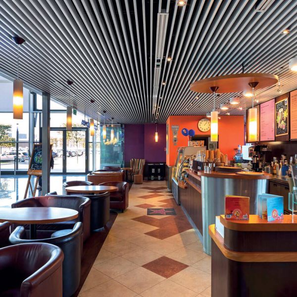 KNAUF Ceiling Armstrong V-P500 Acoustical Baffles planks with a white non perforated panel in a retro restaurant