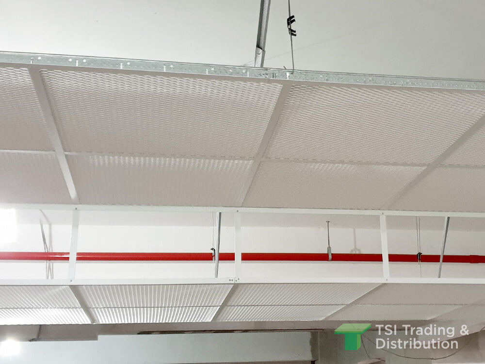 A white metal mesh ceiling with a red pipe