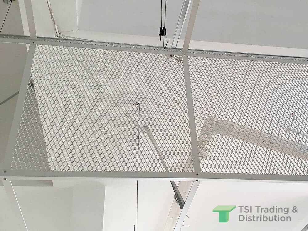 The opposite side of a close up view of white metal mesh on a ceiling