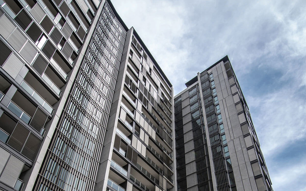 A low angle view of a tall building with large windows and balcony