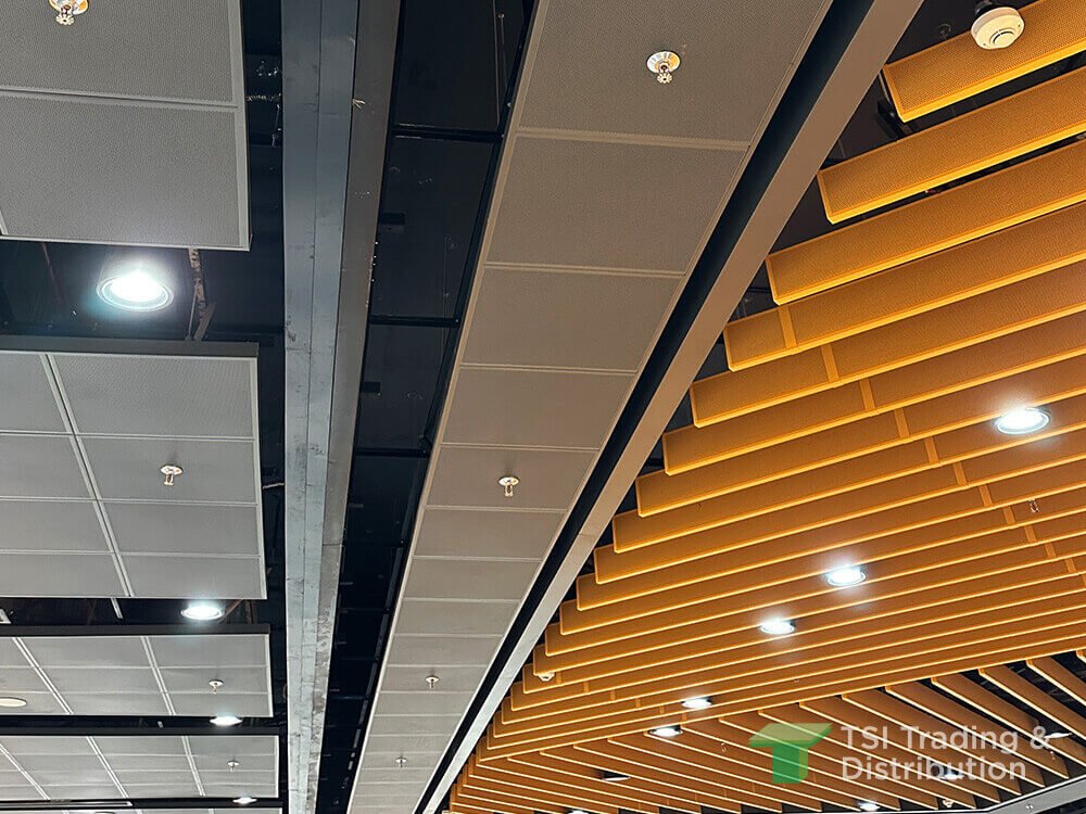 A side view of intersecting layout ceiling planks in light brown with grey ceiling tiles and recessed lights